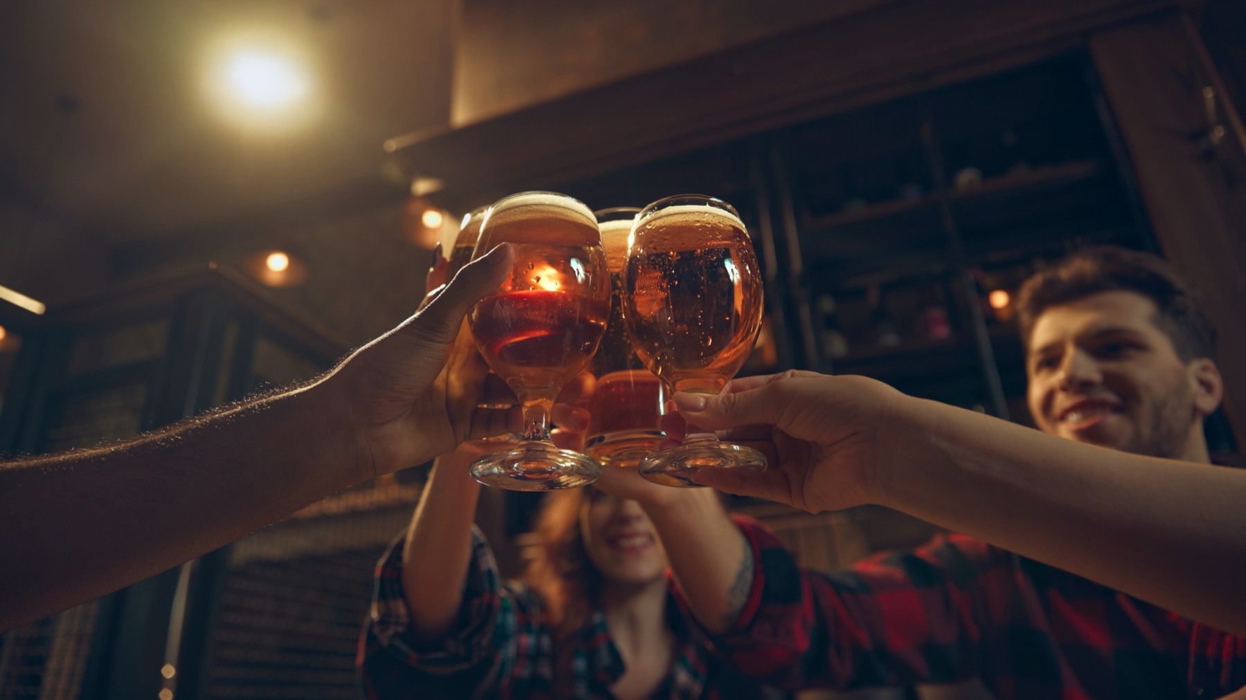 Friends raising glasses of beer together in warm light
